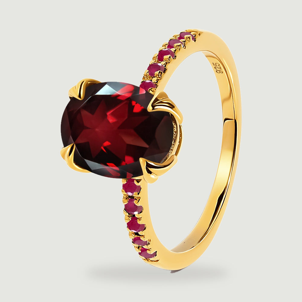An angled yellow gold vermeil ring shows its oval red gemstone and ruby set band.