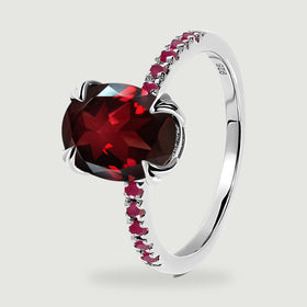 An upright sterling silver ring reveals the faceted red center stone and red accents on both shoulders.