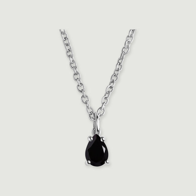 A black pear-shaped pendant with four silver-colored prongs is shown with its oval-link chain on light gray.