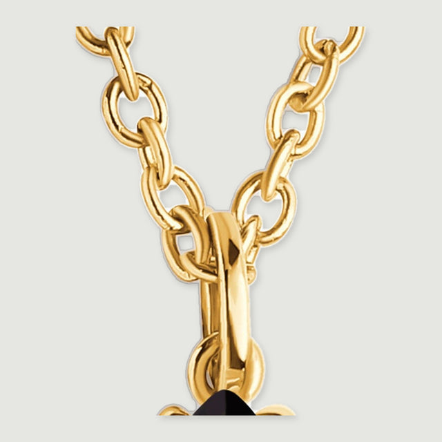 Interlocking yellow gold-colored chain links meet the polished loop above the black pendant.
