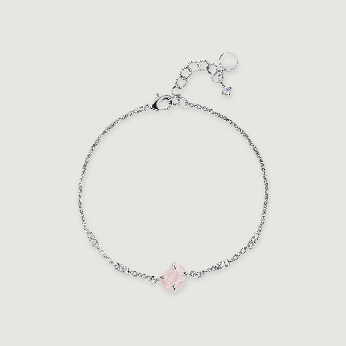 A silver tone chain curves around a raw pink quartz centerpiece with four clear accent stones and an adjustable clasp.
