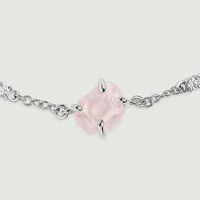 A magnified bracelet detail shows a translucent pink crystal, silver tone prongs and linked clear stones on a light grey background.
