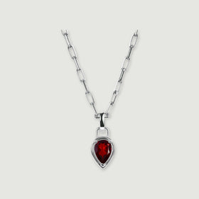 A silver-tone rectangular-link chain holds a deep red pear-shaped pendant against a softly shadowed gray surface.