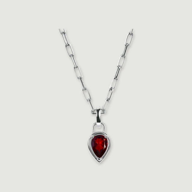 A silver-tone rectangular-link chain holds a deep red pear-shaped pendant against a softly shadowed gray surface.