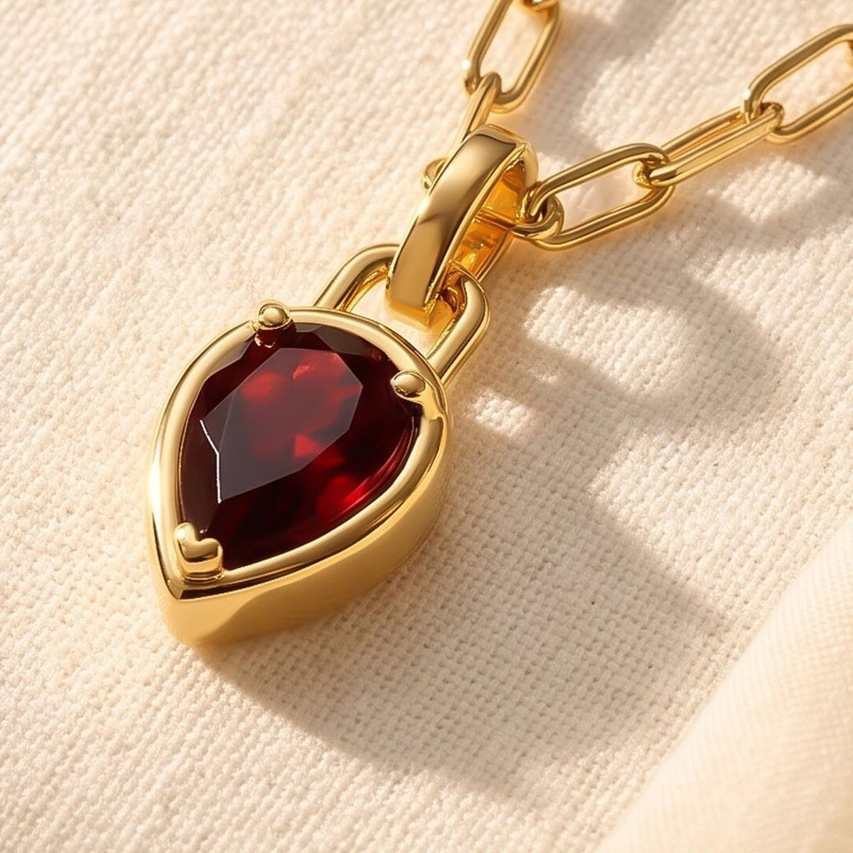 The gold-tone pendant is shown at an angle, revealing its raised rim and the depth of the red stone setting.
