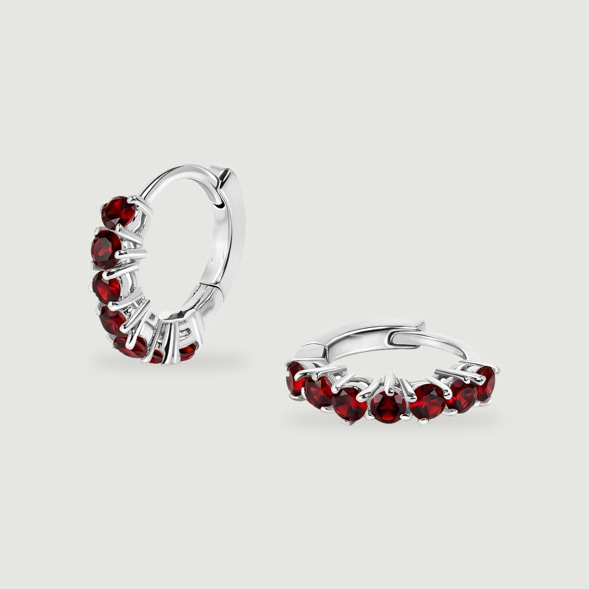 A pair of white rhodium plated garnet hoops shows the curved backs and hinged closures.