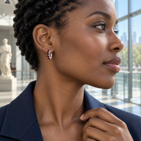 A woman with short twists wears a white rhodium plated garnet hoop in a bright museum.