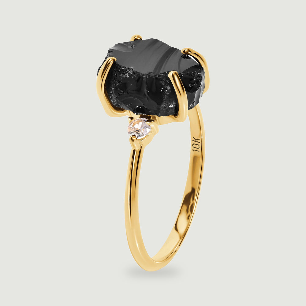 A side view shows the raised black stone, a clear side stone, and the slim yellow gold band.