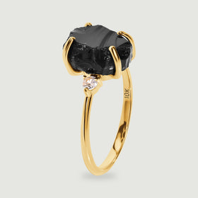 A side view shows the raised black stone, a clear side stone, and the slim yellow gold band.