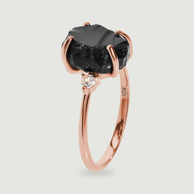 The rose gold ring is shown upright with curved prongs around the uneven black stone.