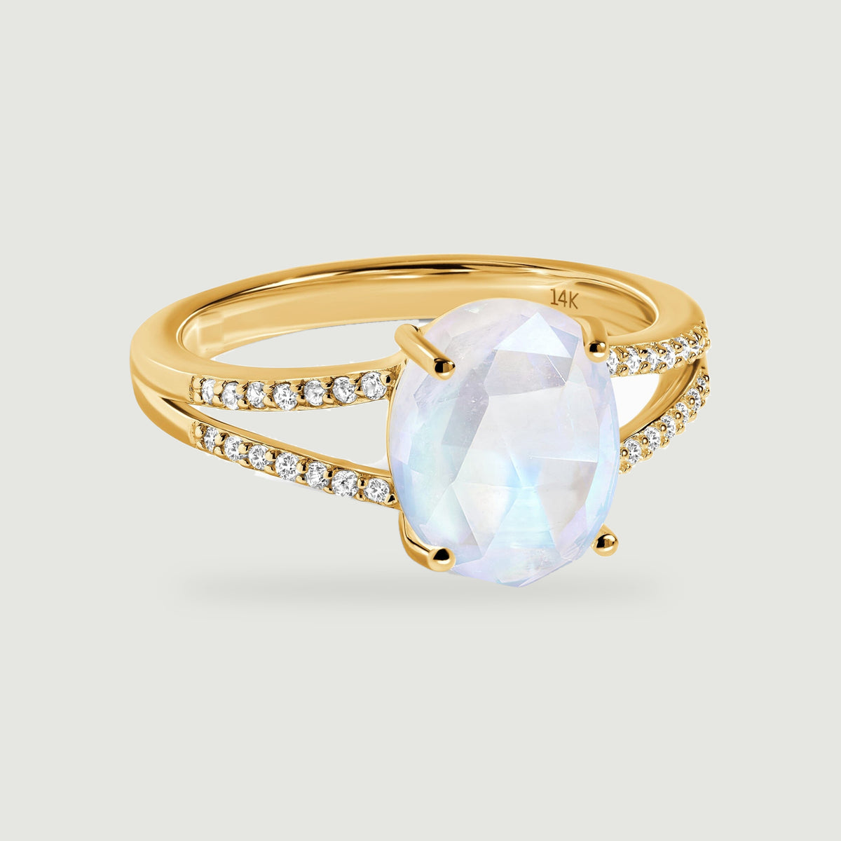 An oval moonstone sits in a yellow gold ring with two diamond-set shoulders.