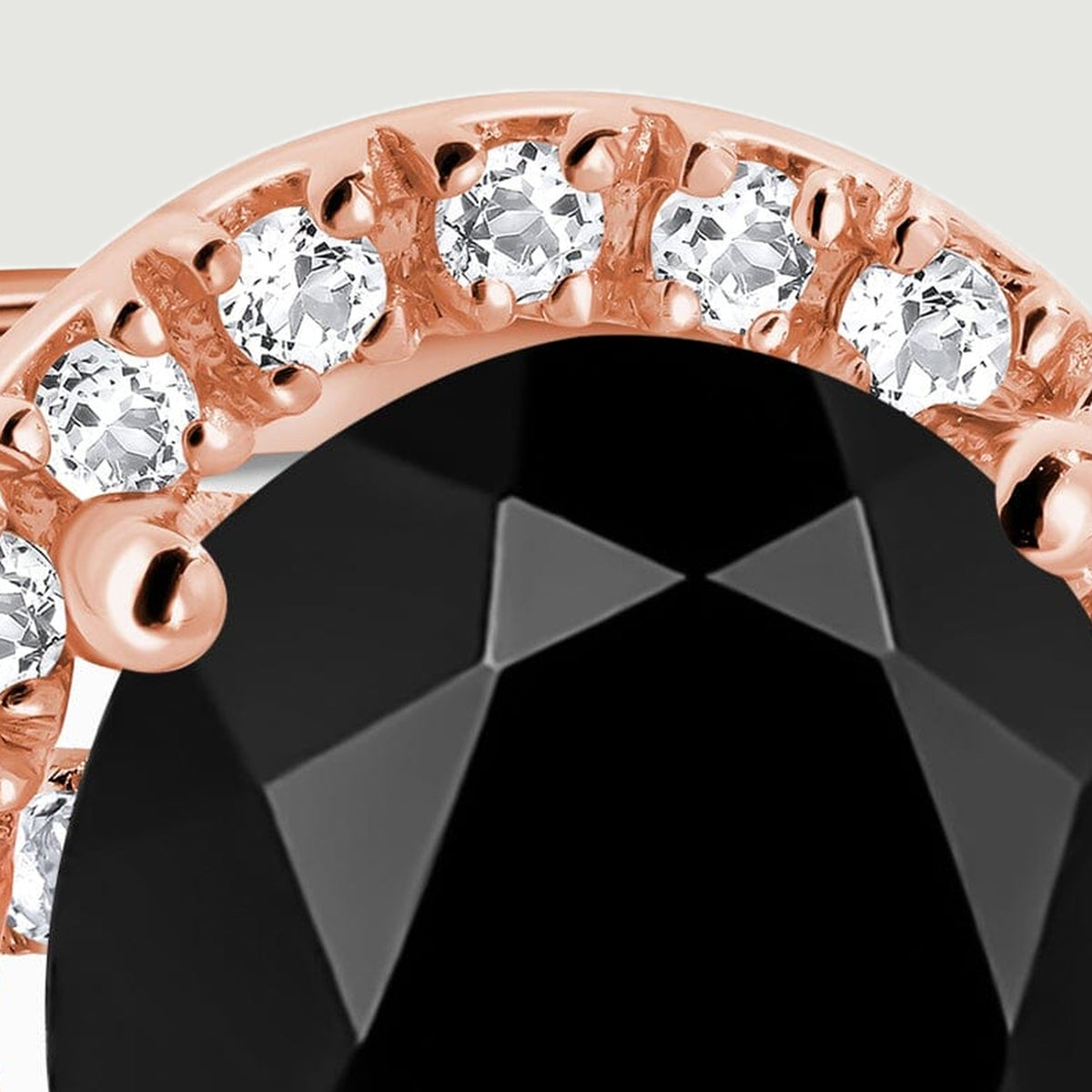 A close view shows the upper halo, rounded rose gold prongs and angular reflections across the black stone.
