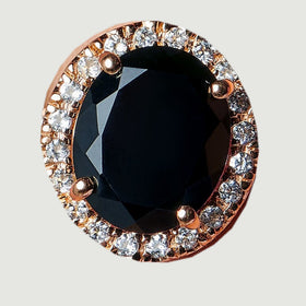 The ring face appears from above with a glossy black oval and a rose gold halo of clear stones.