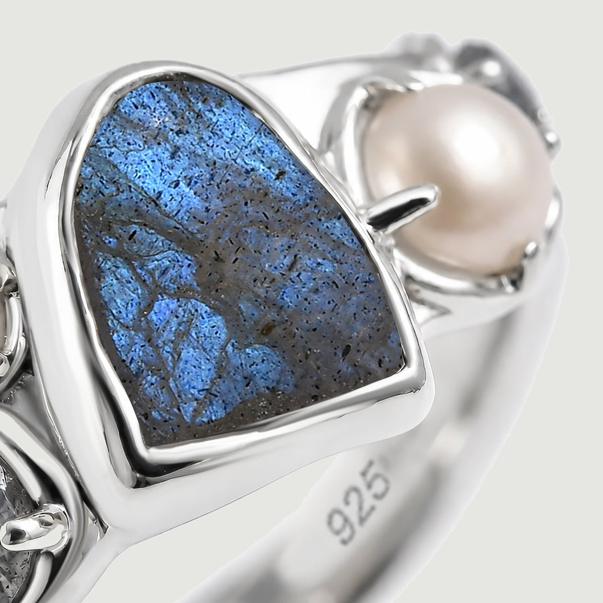 A close view shows the blue texture of labradorite beside a white pearl and polished silver settings.