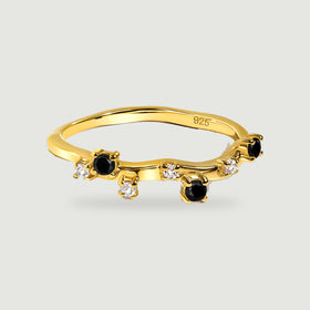A yellow gold vermeil ring with a curved band, round black onyx stones and small clear stones on a light grey surface.