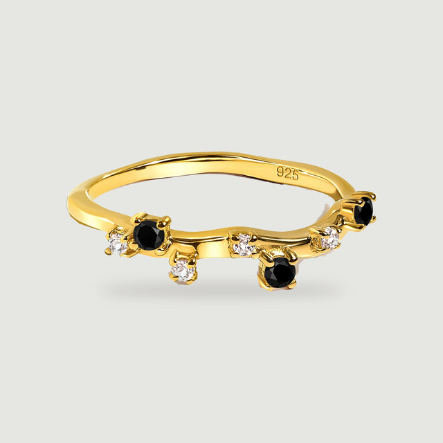 A yellow gold vermeil ring with a curved band, round black onyx stones and small clear stones on a light grey surface.
