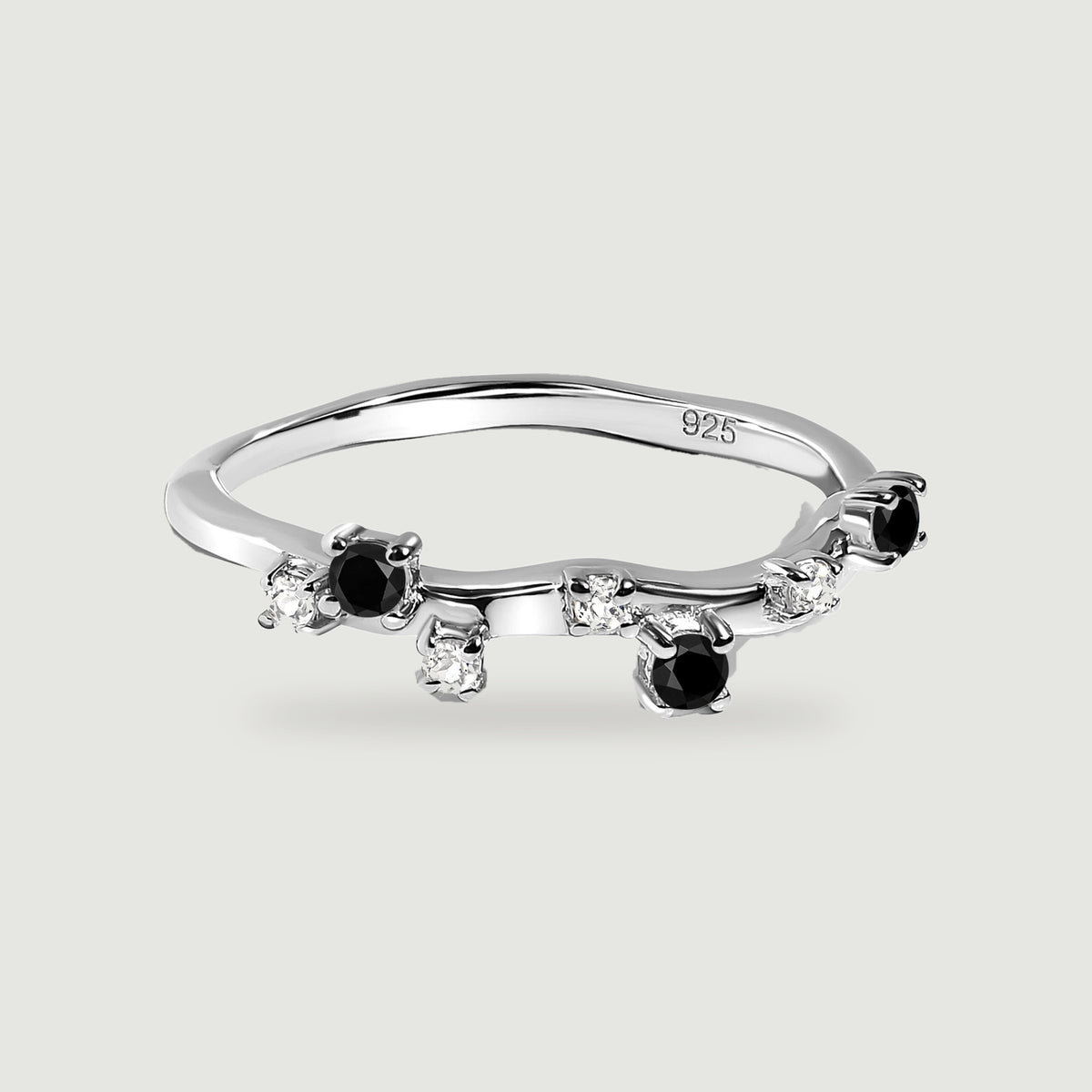 A sterling silver ring with black round stones and clear accents shown from above on a pale grey background.