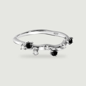 A sterling silver ring with black round stones and clear accents shown from above on a pale grey background.
