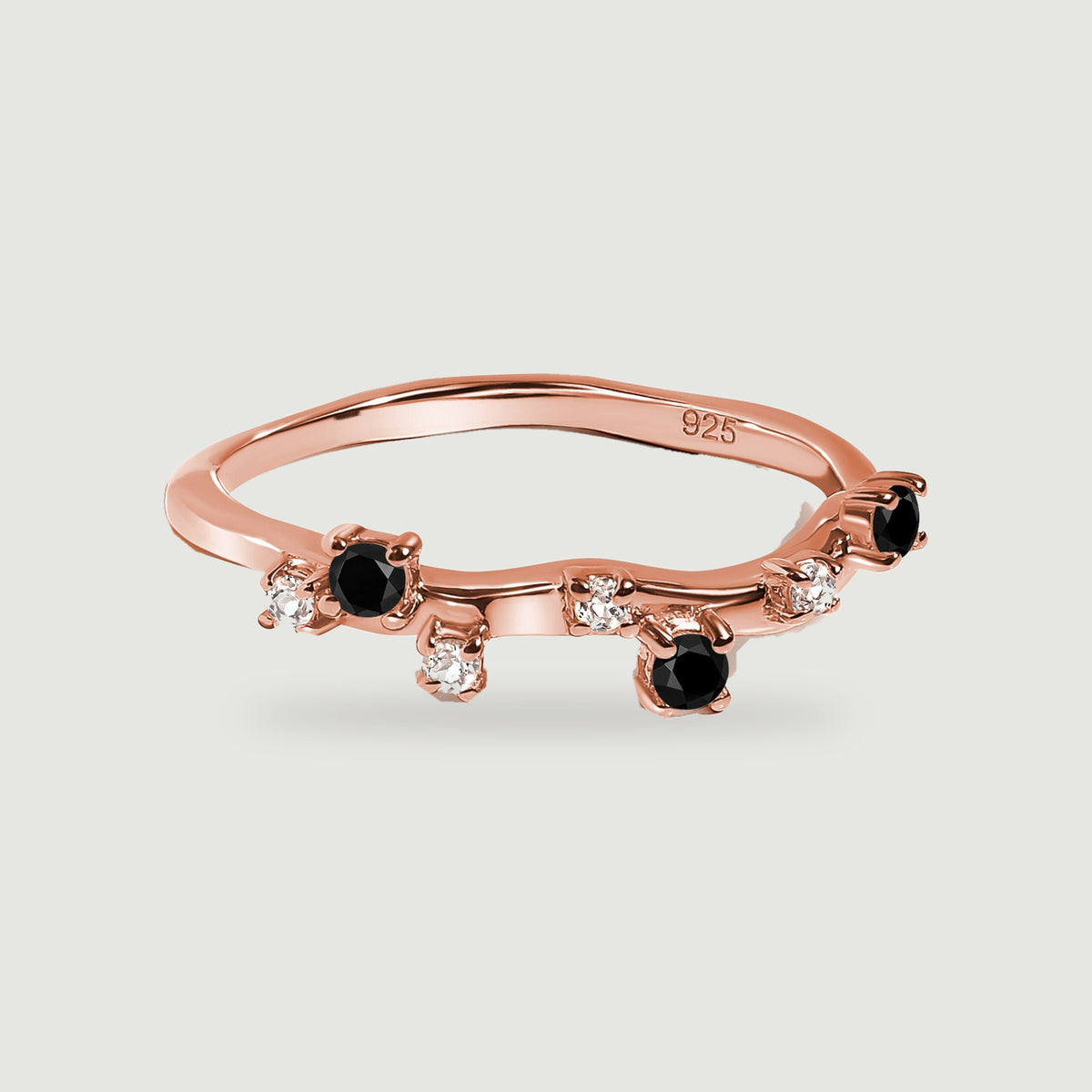 A rose gold vermeil band with alternating black onyx and clear stones in a low three-quarter view.
