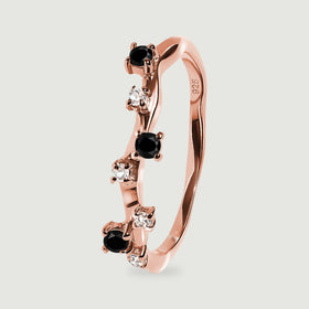 A rose gold vermeil ring in side view shows polished curved metal and small prong-set black and clear stones.