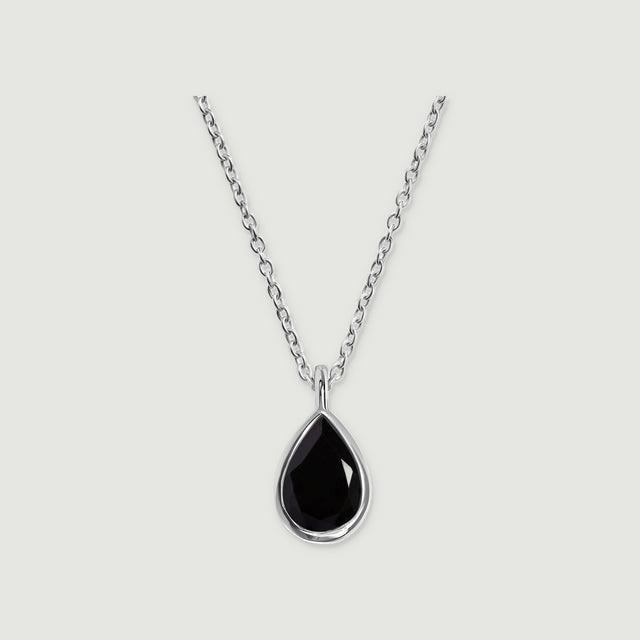 A sterling silver bezel frames a black pear-shaped pendant beneath an oval-link chain on a gray background.