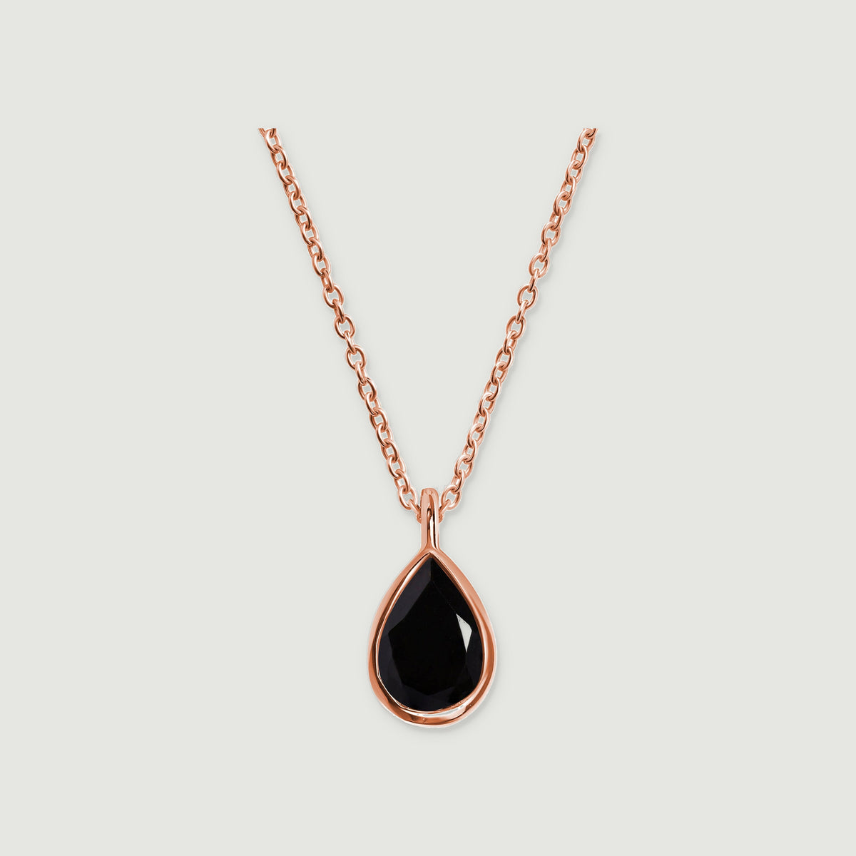 A rose gold vermeil necklace displays a glossy black teardrop stone and a narrow polished bail on light gray.