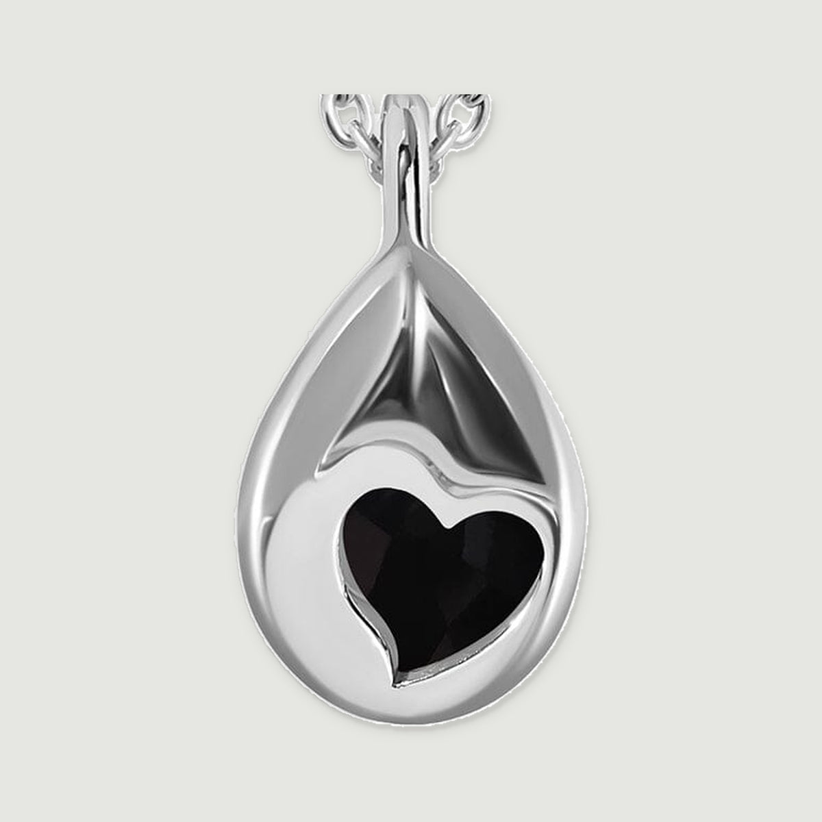 A close view of the silver pendant back reveals a heart-shaped aperture and its smooth curved pear outline.