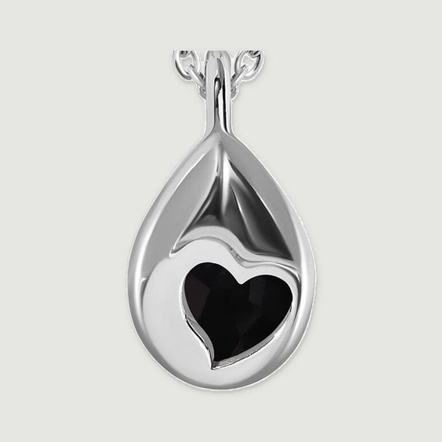 A close view of the silver pendant back reveals a heart-shaped aperture and its smooth curved pear outline.