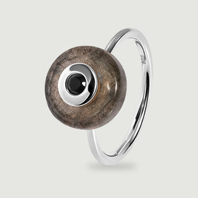 A sterling silver ring displays a circular labradorite disc and a black faceted centre stone with the polished band visible behind it.