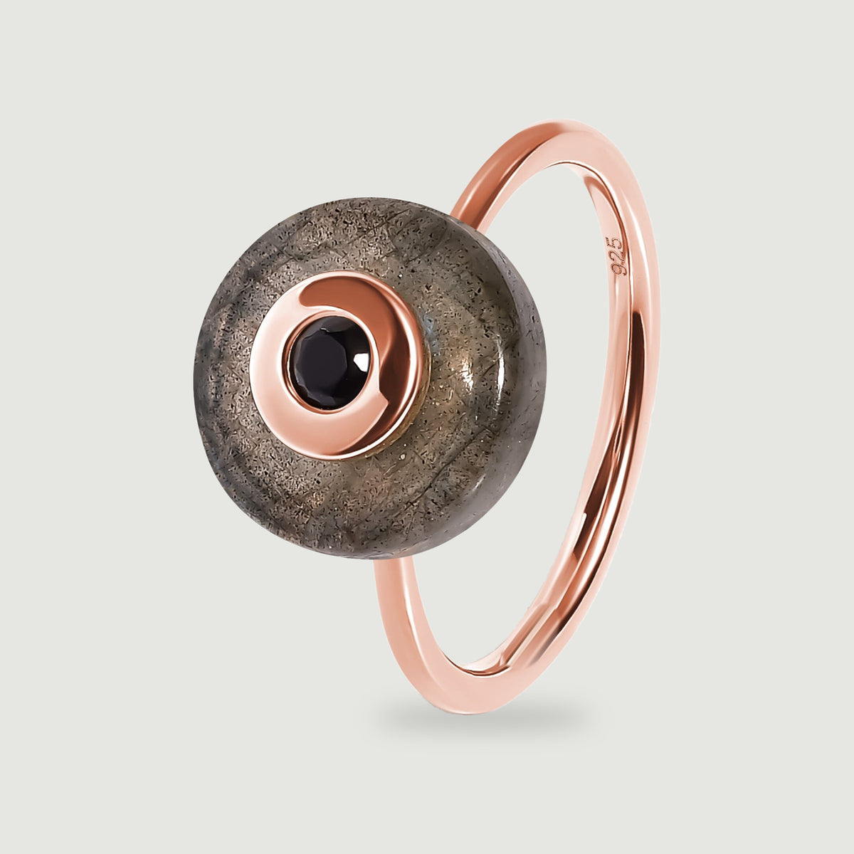 A rose gold vermeil band curves behind a grey labradorite disc with a black centre stone in this upright ring view.