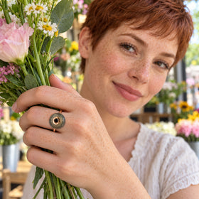 A freckled woman wears the rose gold vermeil labradorite ring while holding fresh flower stems in a bright flower shop.