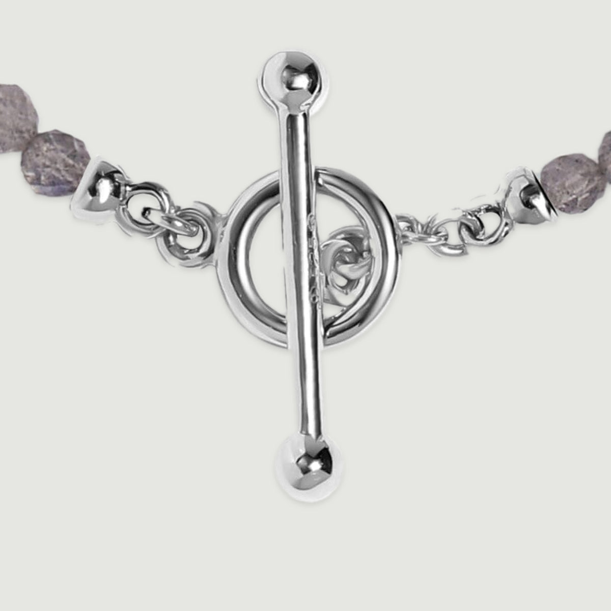 A close view shows the silver bar clasp, circular fastening ring and small connecting links beside grey faceted beads.