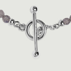 A close view shows the silver bar clasp, circular fastening ring and small connecting links beside grey faceted beads.