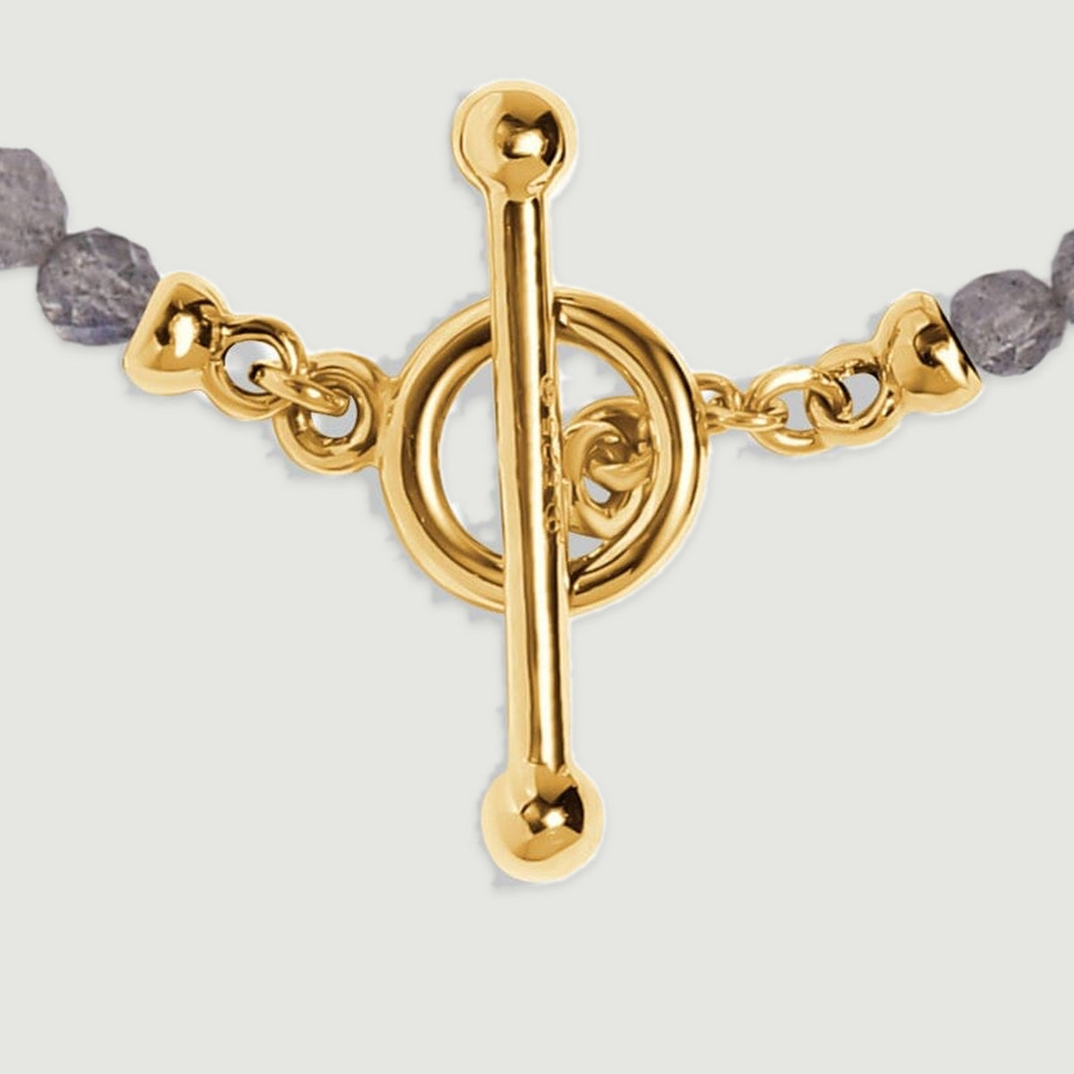 The yellow gold bar clasp and polished circular ring are shown close up with grey labradorite beads at each side.