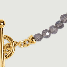 A yellow gold end cap and short oval links connect the circular clasp to a row of grey labradorite beads.