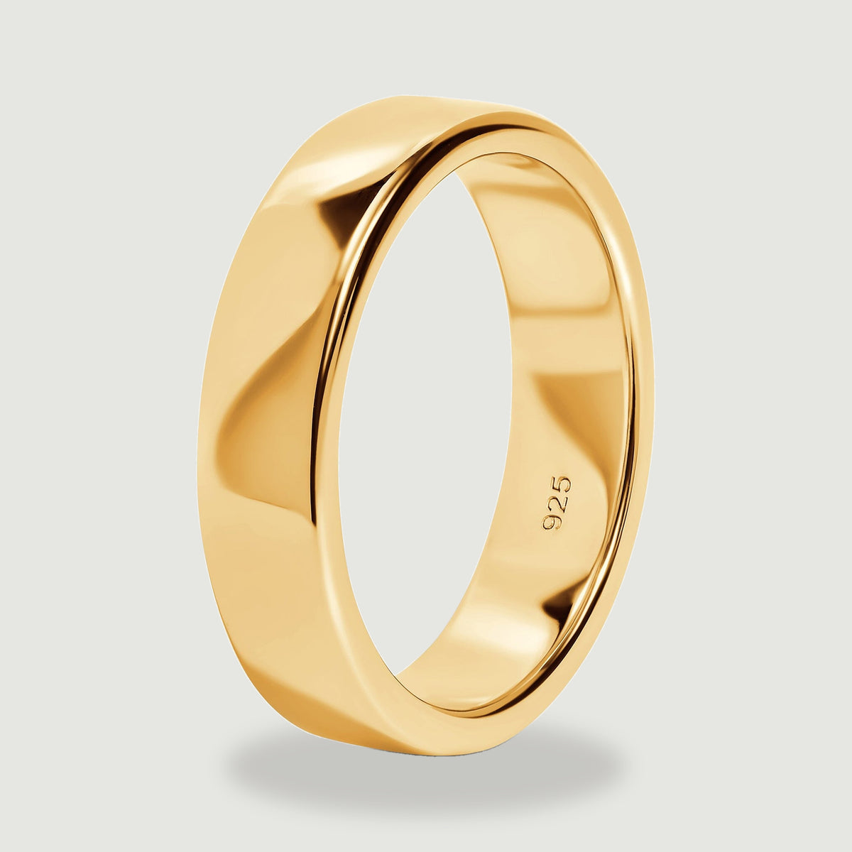 The yellow gold band stands at an angle, showing its rounded rim and smooth inner wall.