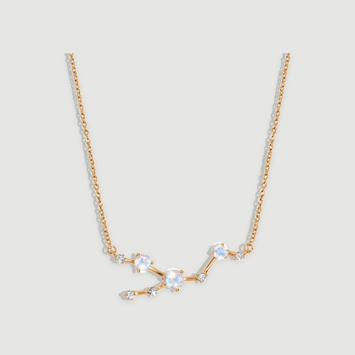 A yellow gold necklace displays three round moonstones and five small clear stones along an angular linked centerpiece.