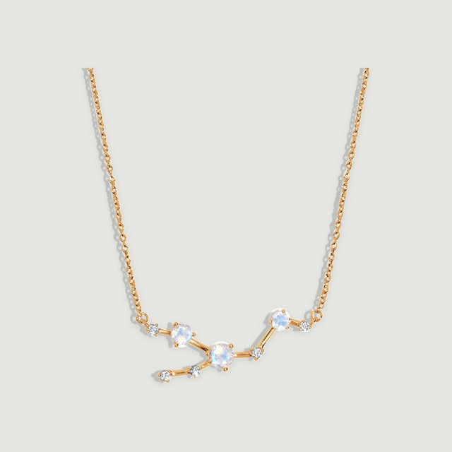 A yellow gold necklace displays three round moonstones and five small clear stones along an angular linked centerpiece.