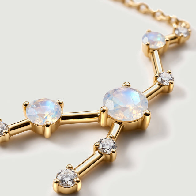 A close view shows blue reflections within faceted moonstones beside rounded yellow gold prongs and clear accent stones.