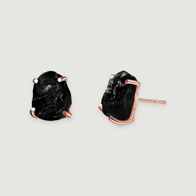 Black obsidian stud earrings show rough stone faces and rose gold settings against light gray.