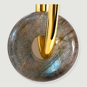 A close view shows blue flashes and dark speckles in a labradorite disc threaded onto a yellow gold hoop.