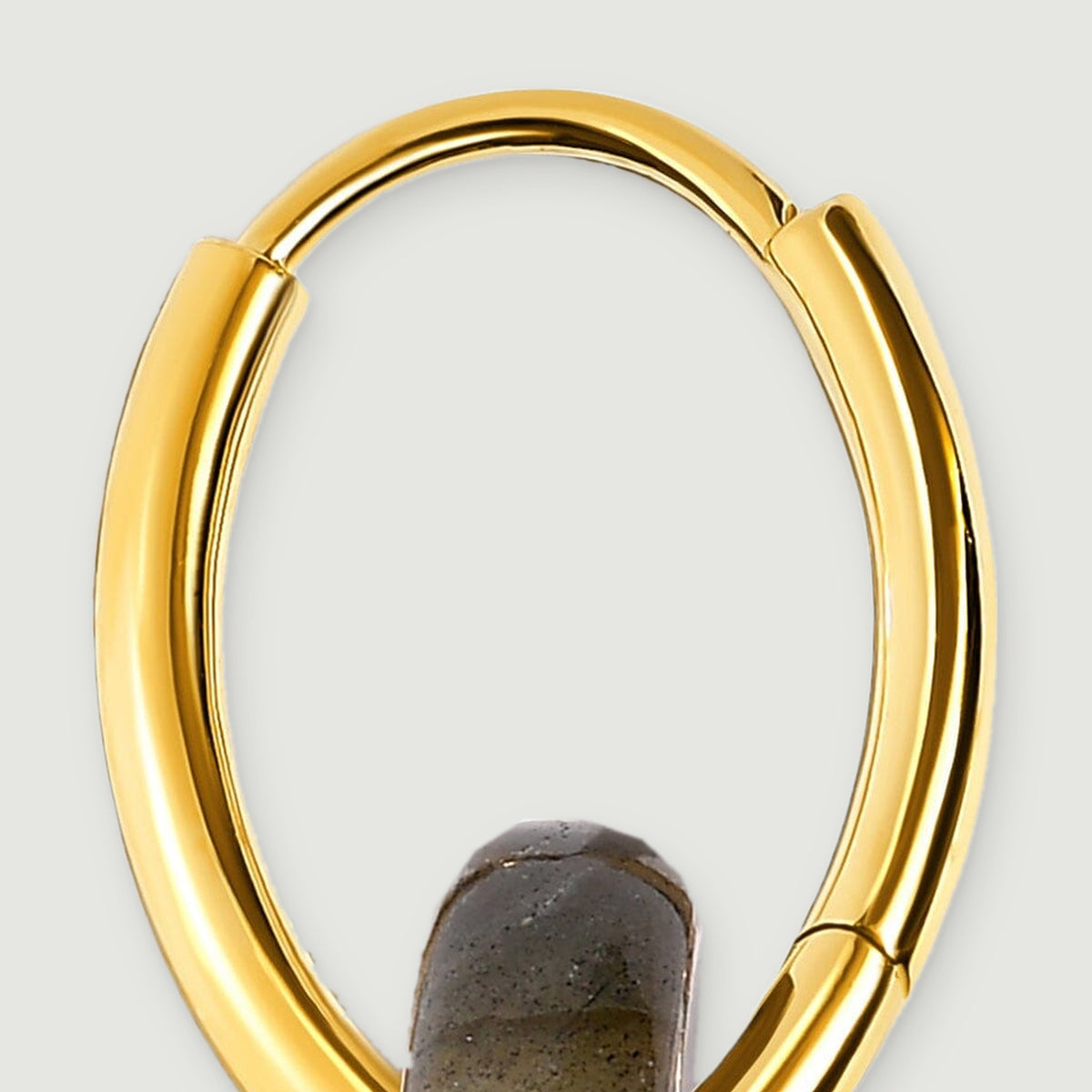A detailed view of a yellow gold hoop shows its rounded upper arc and smooth reflective sides.