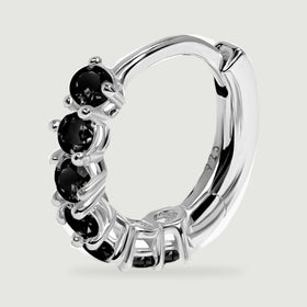 A sterling silver hoop earring is shown at an angle with black stones, a curved inner band and a hinged clasp.