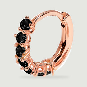 A rose gold vermeil hoop earring shows its row of round black stones and polished curved band.