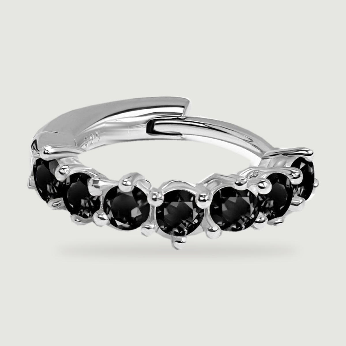 Round faceted black stones sit in silver prongs along the front of a flat hoop earring.