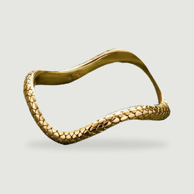 An angled yellow gold ring displays its sculpted contour and reflective textured edge.