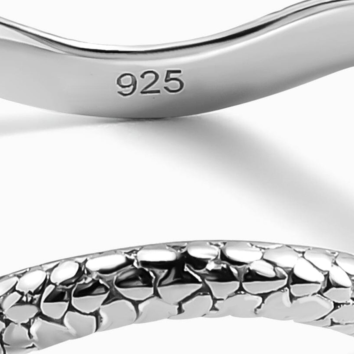 The silver ring reveals a 925 hallmark on its smooth inner band above the textured front edge.
