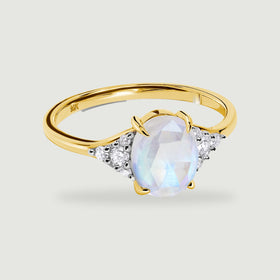 A yellow gold band curves around a blue-flashing oval moonstone flanked by clear diamond clusters.