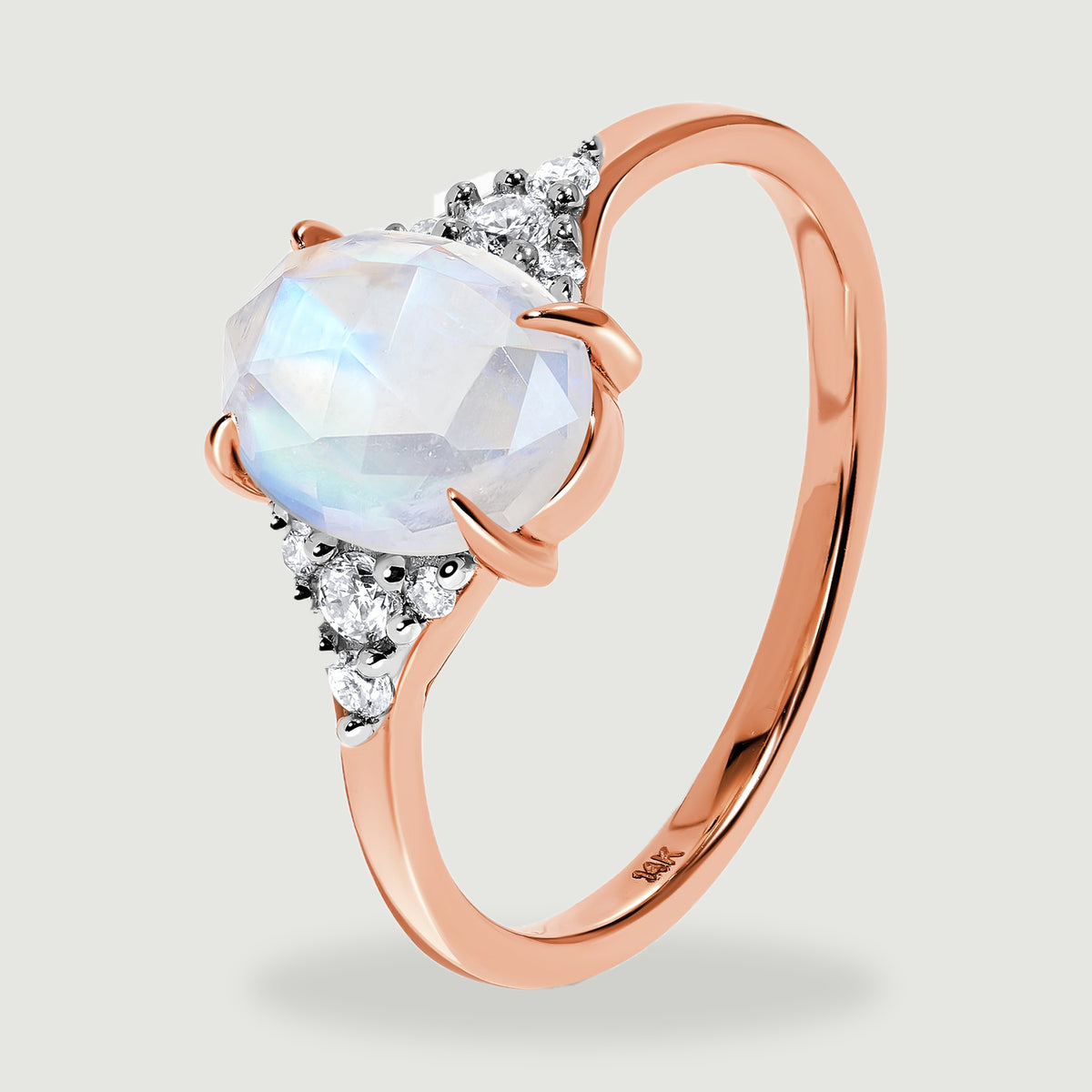 An angled rose gold ring shows the raised oval moonstone setting and the smooth inner band.