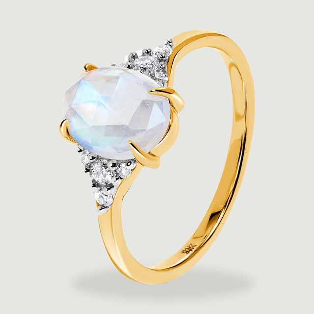 The yellow gold ring stands at an angle with the oval stone and diamond clusters facing forward.